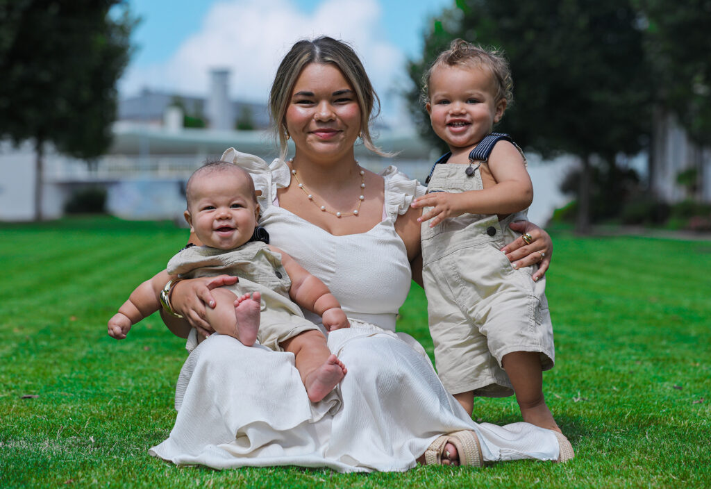 Outdoor lifestyle shoot in downtown Atlanta featuring a woman sitting side by side with her two children on green grass — part of our photography portfolio.